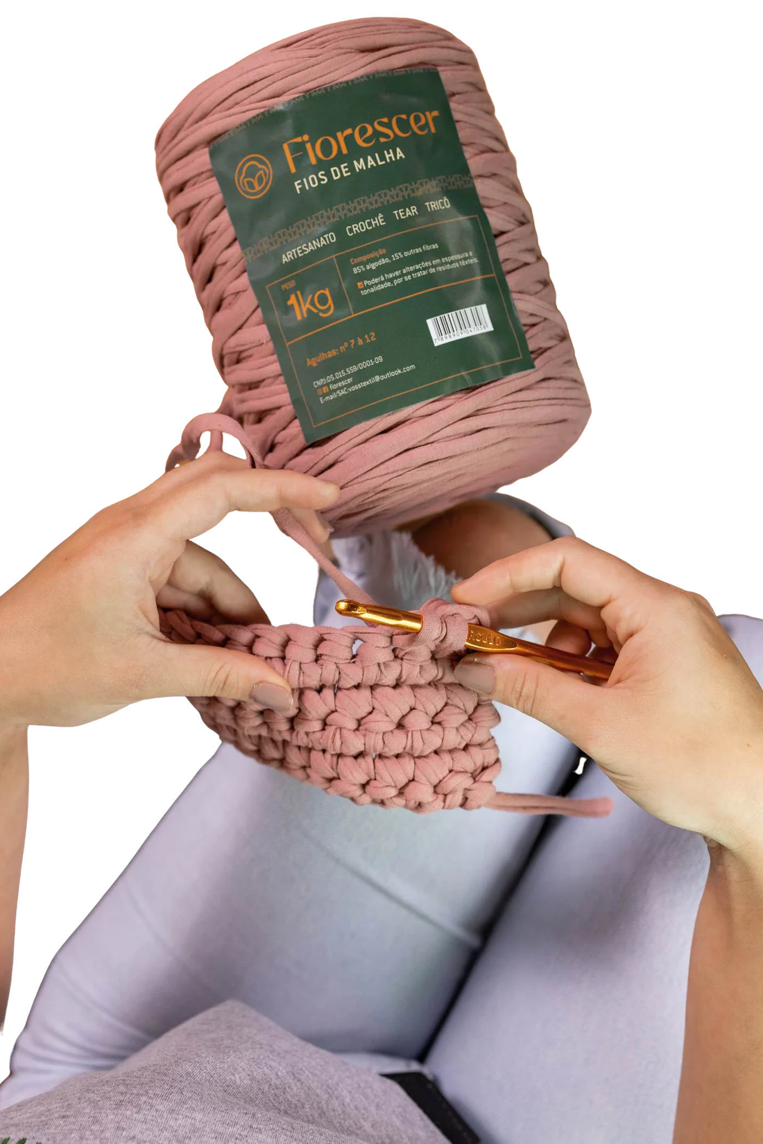 Mãos crochetando um cesto de fio de malha rosa